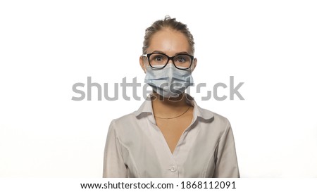 Young blond nurse in eye glasses looking at the camera wearing white medical uniform isolated on white background. 