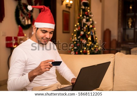 Young Man sitting at home on Christmas doing online shopping