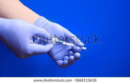 Male nurse using needle and syringe on blue background