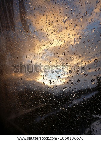 Moody vertical sunrise view out a window with water droplets