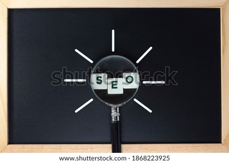 SEO, Search engine Optimization concept.  SEO text on block letters with magnifying glass on the black background 