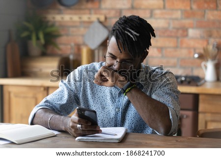 Stressed young biracial guy in glasses feeling confused of getting message with unexpected bad news. Unhappy african man getting bank debt notification on cellphone, thinking of problem solution. Royalty-Free Stock Photo #1868241700