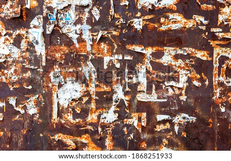 Weathered grunge rusty metal texture with scraps of old paper as background