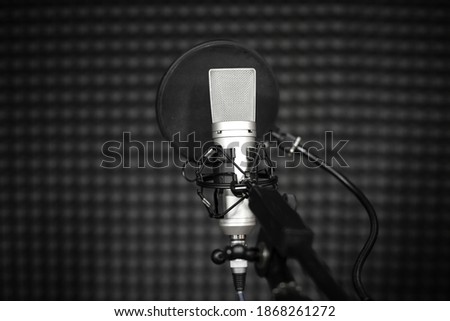 Voice microphone with shock mount and pop filter on professional tripod in audio recording vocal studio. Concept of using recording microphone for professional singing and voiceover. Black and white.