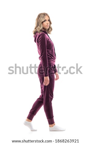 Side view of relaxed calm young woman in sweatshirt and sweatpants walking. Full body length isolated on white background.  Royalty-Free Stock Photo #1868263921
