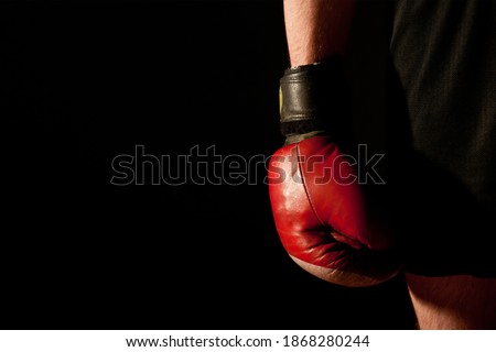 A part of the fighter with a hand in the red glove on the dark background
