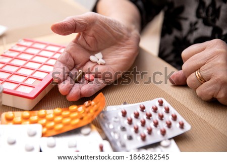 Older women taking medications at table, Senior woman preparing pills , prepare daily medicine tablet in pillbox Royalty-Free Stock Photo #1868282545
