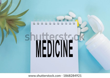 Medicine inscription on a Notepad, near tablets and a flower, top view.