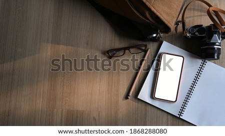 Top view of Photographer work place with camera, notebook, smart phone with blank screen and copy space.