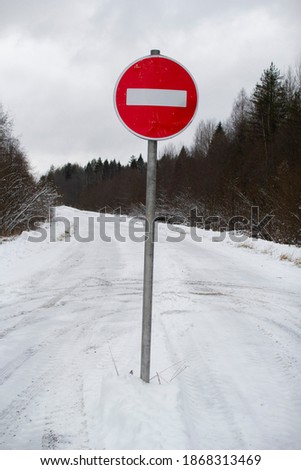 Stop sign on a winter forest road . Travel is prohibited