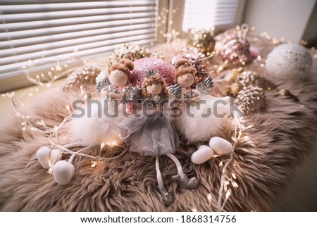 Beautiful angel dolls and shiny bauble on window sill indoors