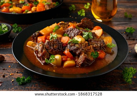 Beef Stew with carrot and baby potato in black plate on wooden table Royalty-Free Stock Photo #1868317528