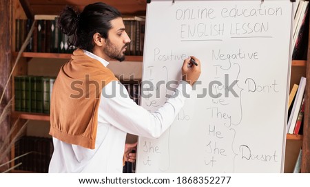 Online Learning. Indian Male Teacher Teaching Students English Language Distantly Writing On Blackboard Grammar Rules Standing Indoors. Knowledge, E-Teaching And Learning, Modern Education. Panorama