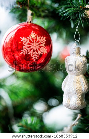 Christmas background. Detail view of red and silver baubles and festive decorations hanging on a green christmas tree.