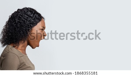 Angry black woman shouting towards copy space over grey background, panorama, side view. Furious african american lady screaming loud, saying about her problems or needs, expressing negative emotions Royalty-Free Stock Photo #1868355181