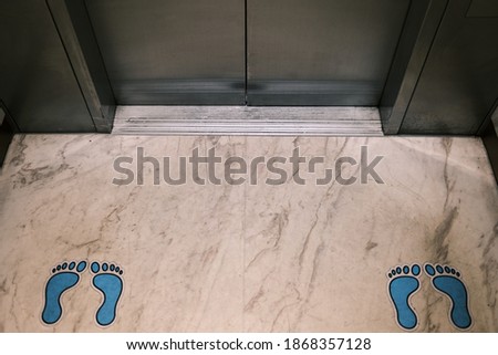 Blue colored footprints symbolized social distancing in the elevator