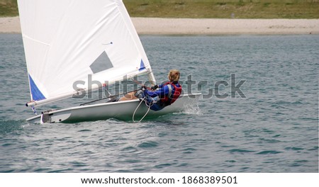 Young sailor in a small boat sailing on the lake
