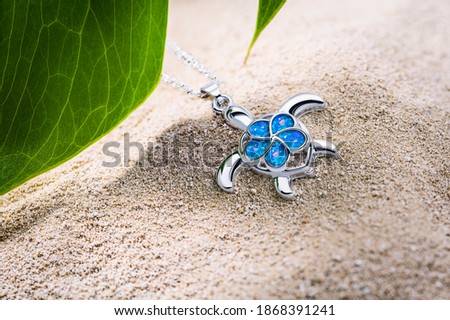 Silver turtle with opals on sandy beach
