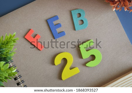 February 25, Cover design in natural concept with a brown notebook and colorful wooden alphabet.