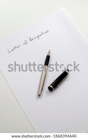 employee writing resignation letter on a blank paper. vertical focus. top view