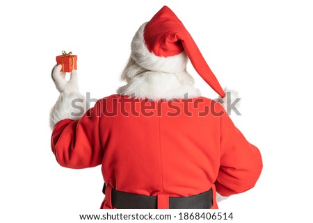 Rear view of Santa Claus with raised hand and gift, concept of handing over for christmas holidays. Isolated white background. Royalty-Free Stock Photo #1868406514