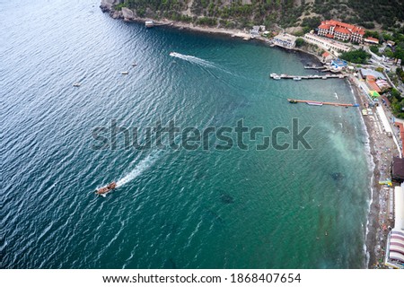 The sea with a narrow coastline and many vacationers on the beach. Shooting from the air.