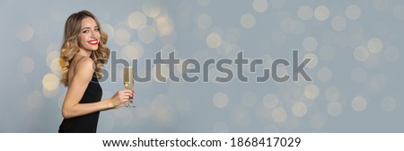 Beautiful woman holding glass of champagne on grey background, space for text. Christmas party, banner design