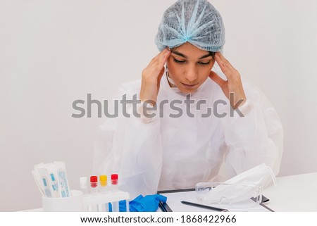 Tired female doctor in a protective clothing sits in the doctor's office.Coronavirus concept.Copy space for text
