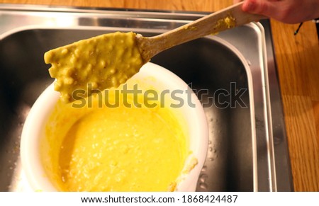 Close up of a wooden fork filled with saffron cookie dough. Held by a hand in a kitchen. Aerial view. Stockholm, Sweden.