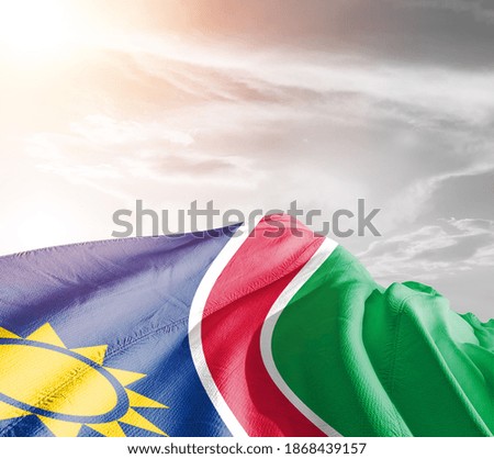 Namibia national flag cloth fabric waving on beautiful sky background.