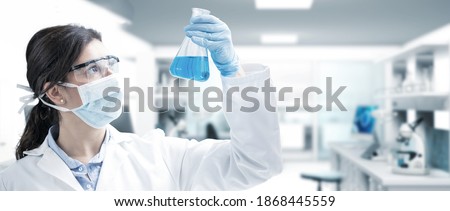 Female scientist measuring blue liquid in a flask at a chemical laboratory. Concept about biochemistry or pharmaceutical research and development.Scientific researcher work. Royalty-Free Stock Photo #1868445559