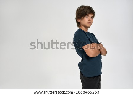 Little sportive boy child in sportswear looking at camera, posing while standing with arms crossed isolated over white background. Sport, training, fitness, active lifestyle concept. Horizontal shot