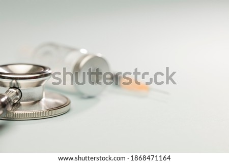  stethoscope with vaccine in vial, syringe, soft blue background