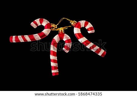 three red striped Santa candies are stacked on a black background. To isolate the framing. Christmas toys for Christmas, New year, winter holiday atmosphere for lovers and loved ones