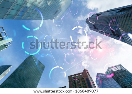 Abstract technology icons hologram on low, wide angle view of glass and steel contemporary skyscrapers in financial downtown. The concept of success in hi-tech industry. Double exposure.