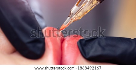 Banner Process woman applying permanent tattoo makeup on lips in beautician salon. Royalty-Free Stock Photo #1868492167