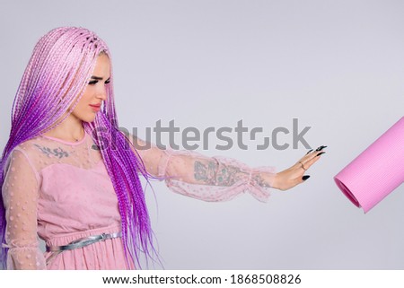 A girl with long pink hair braids wearing a elegant dress , gesturing a refuse to a yoga mat. White background.