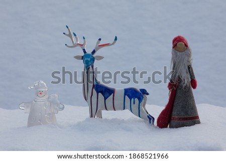 Santa Claus, snowman and Christmas deer in the snow