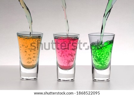 Three alcoholic multicolored alcoholic shots for advertising layout.