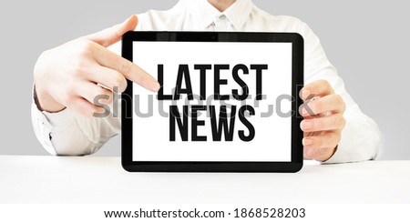 Text Latest News on tablet display in businessman hands on the white bakcground. Business concept