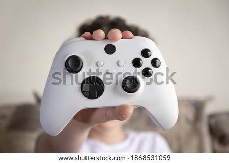 Kid holding next gen game controller. Royalty-Free Stock Photo #1868531059