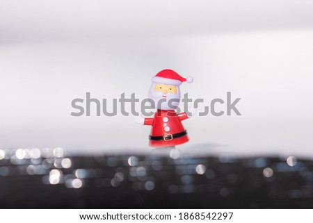 Funny miniature Santa claus doll which The foreground is bokeh sparkling in the winter atmosphere in the snow on white background. merry christmas and happy new year concept