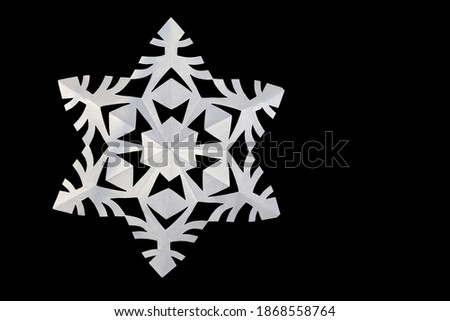 White paper snowflake isolated on black, copy space. Handmade new year decoration