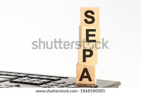 Concept image a wooden block and word - SEPA Single Euro Payments Area - on white background. The cubes are located on the keyboard. Selective focus. SEPA - Single Euro Payments Area