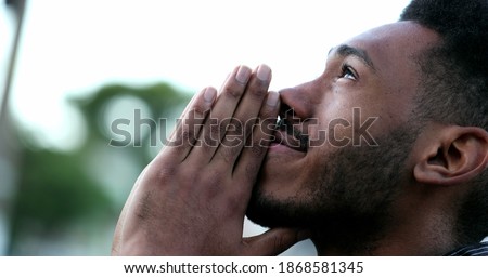 Spiritual young black African man praying to GOD. Person looking to sky with HOPE and FAITH Royalty-Free Stock Photo #1868581345
