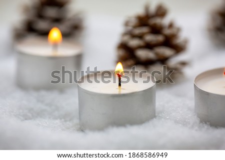 Tea lights burning in the snow, winter picture