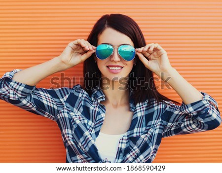 Portrait of beautiful young woman in casual in the city over an orange background