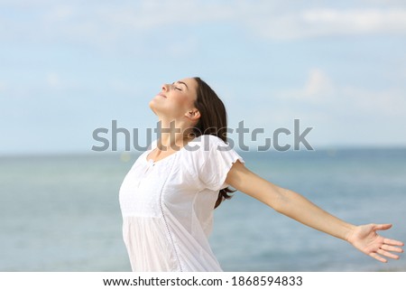 Relaxed woman breathing fresh air and spreading stretching arms on he beach