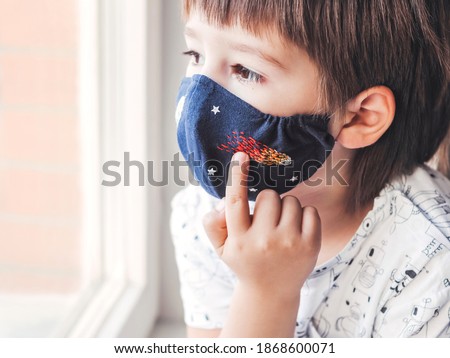Boy with handmade protective mask on face. Fabric mask with embroidered space theme - comet, spaceship and stars. Stay home. Quarantine because of coronavirus COVID19. 