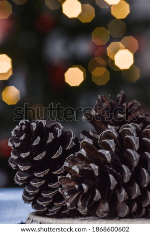christmas pine cones with illuminated christmas tree in the background